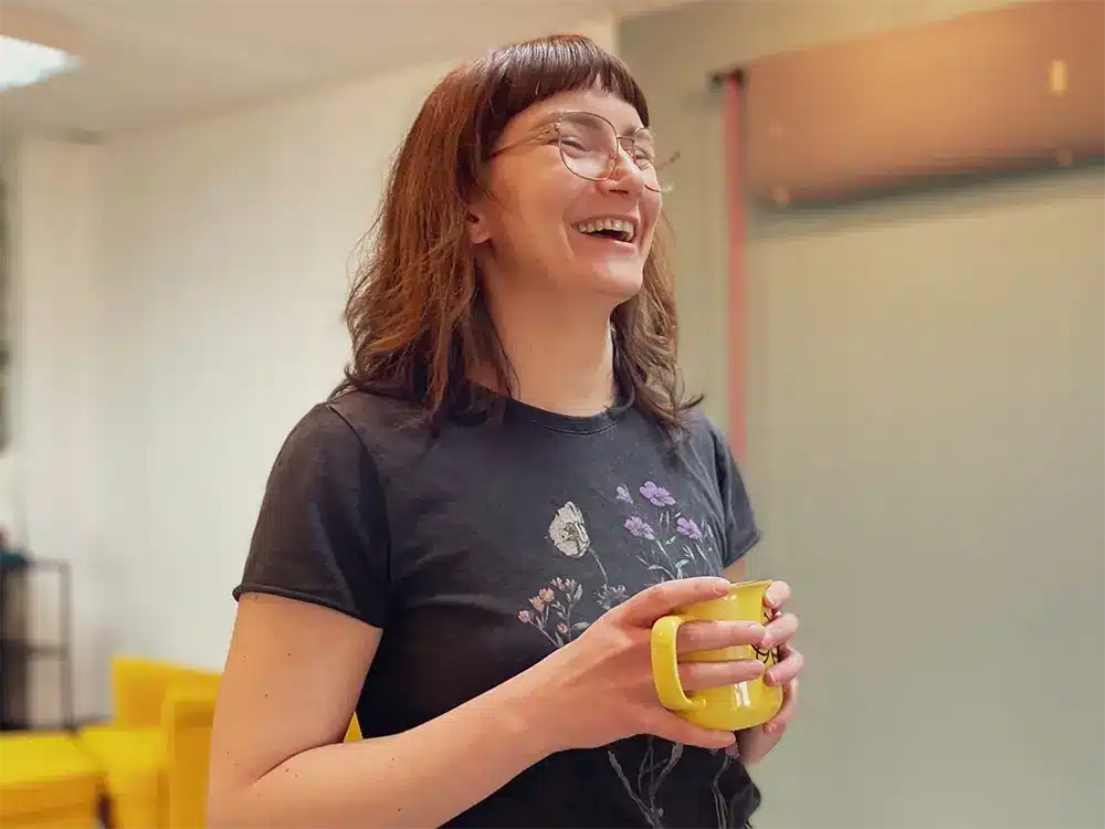 Lächelnde Mitarbeiterin der Werbeagentur Bumblehouse beim Kaffeepause-Moment im Büro