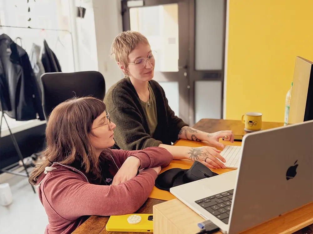 Zwei Grafikdesignerinnen der Bumblehouse Werbeagentur arbeiten gemeinsam an einem Grafikprojekt