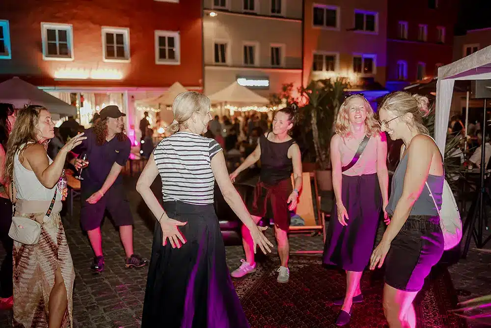 Besucherinnen tanzen ausgelassen beim Stattfest Eggenfelden unter buntem Licht am Abend