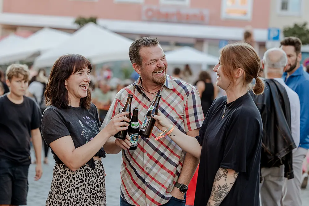 Organisatoren und Bürgermeister stoßen mit Bierflaschen beim Statt Fest in Eggenfelden an