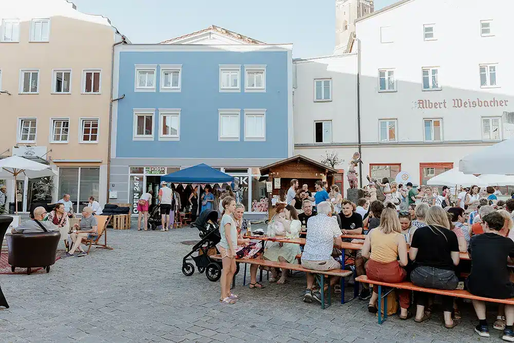 Viele Menschen sitzen auf Bierbänken am Stadtplatz beim Statt Fest in Eggenfelden